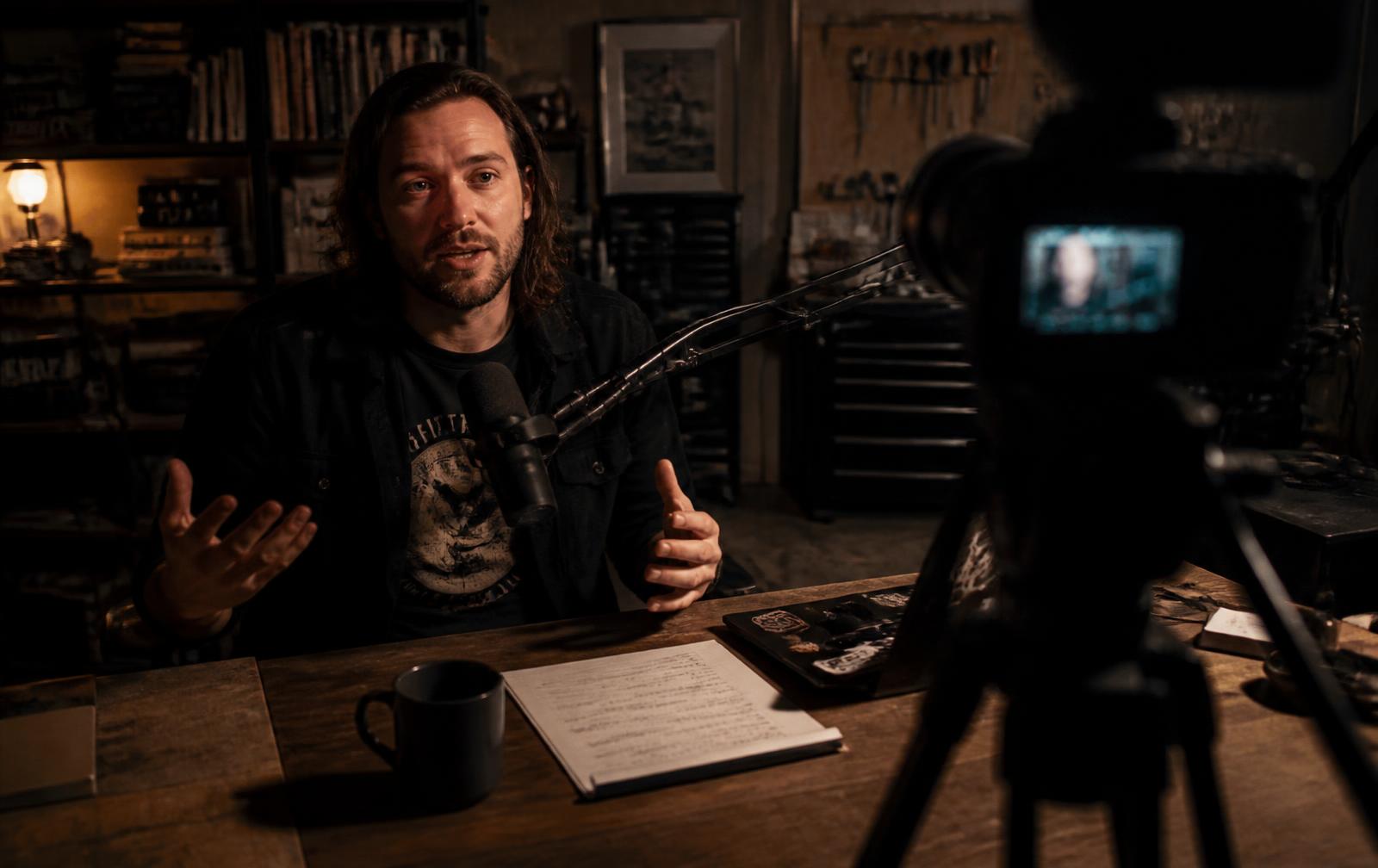A creator hosting a show at a microphone in a lived-in home studio